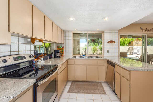 kitchen with light tile patterned flooring, stainless steel appliances, kitchen peninsula, and decorative backsplash