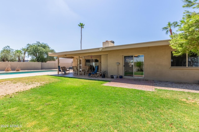 back of property with a patio area, a yard, fence, and stucco siding