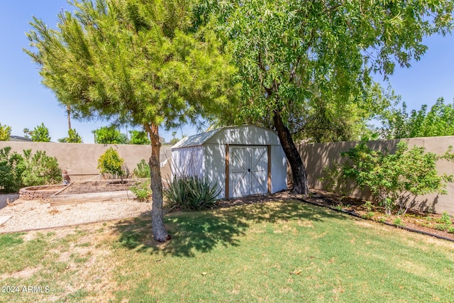 view of yard with an outbuilding, a shed, a fenced backyard, and a garden