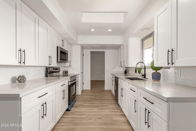 kitchen featuring white cabinets, sink, appliances with stainless steel finishes, and a skylight