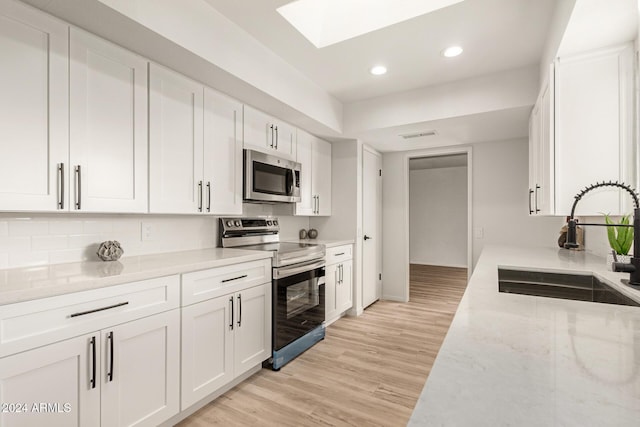 kitchen featuring light stone counters, sink, white cabinetry, and stainless steel appliances