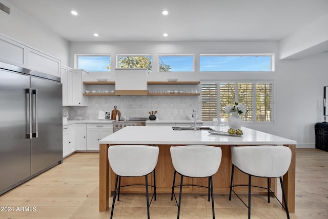 kitchen featuring tasteful backsplash, white cabinetry, an island with sink, sink, and stainless steel appliances