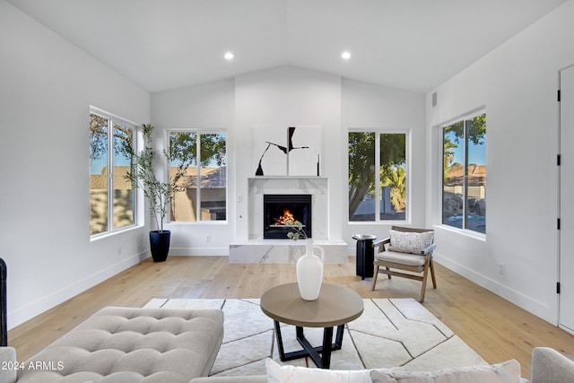 living room featuring a premium fireplace, baseboards, vaulted ceiling, and wood finished floors