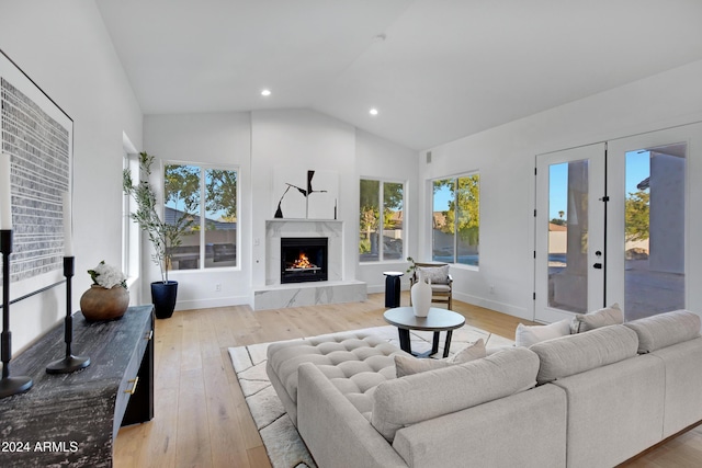 living room featuring recessed lighting, a premium fireplace, baseboards, vaulted ceiling, and light wood-type flooring