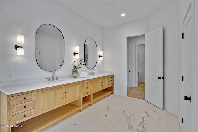 full bathroom featuring marble finish floor, double vanity, a sink, and baseboards