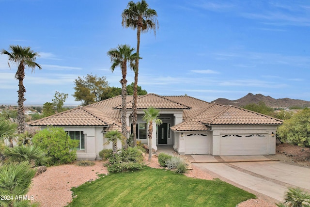 mediterranean / spanish home featuring a garage, a mountain view, and a front yard