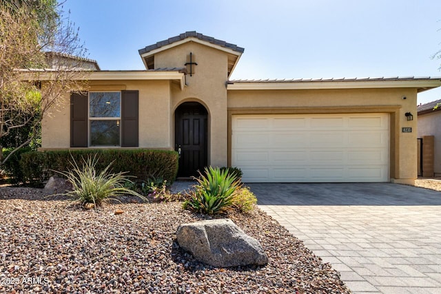 mediterranean / spanish-style house with stucco siding, decorative driveway, and a garage