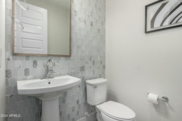 half bath featuring decorative backsplash and toilet