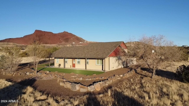 rear view of house featuring a mountain view and a yard