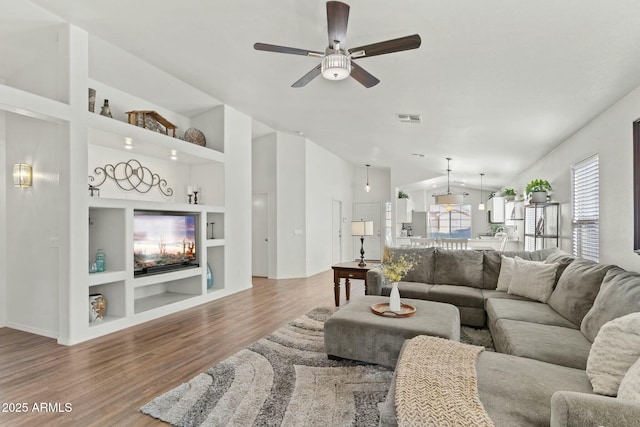 living room featuring ceiling fan, hardwood / wood-style floors, vaulted ceiling, and built in features