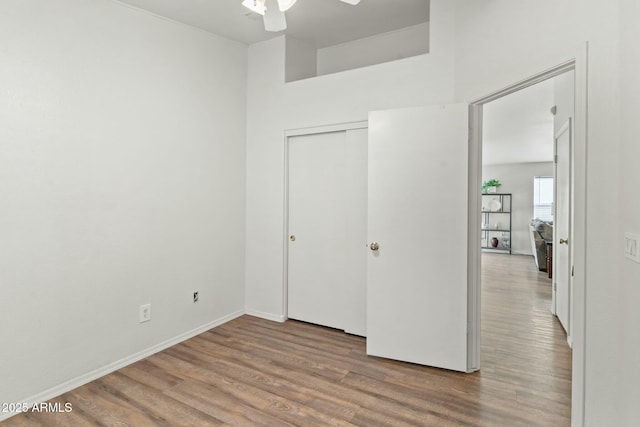 unfurnished bedroom with light wood-type flooring, ceiling fan, and a closet