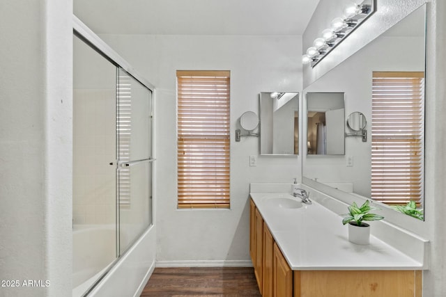 bathroom featuring enclosed tub / shower combo, hardwood / wood-style floors, and vanity