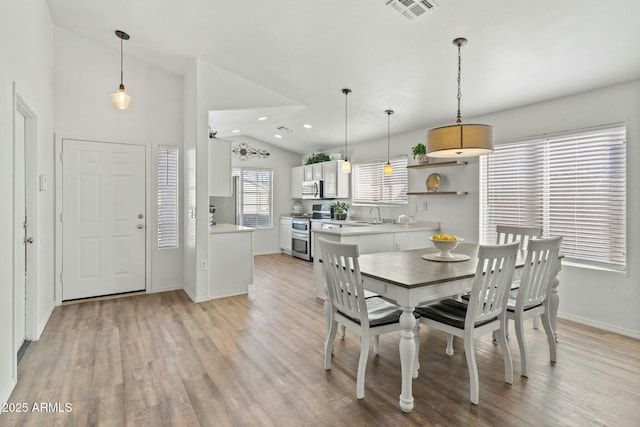 dining space with sink, vaulted ceiling, and light hardwood / wood-style floors