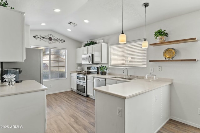 kitchen featuring stainless steel appliances, white cabinetry, sink, and pendant lighting