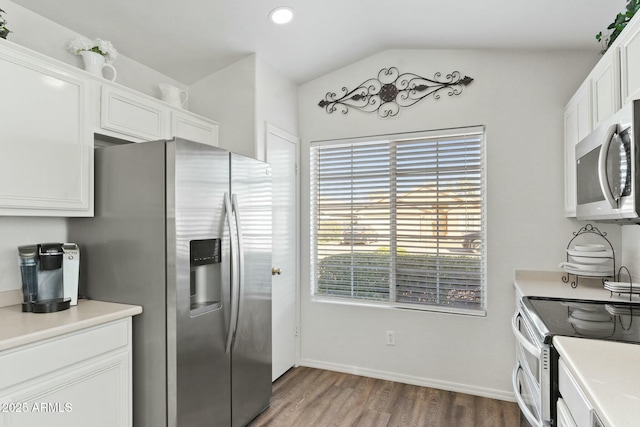 kitchen featuring white cabinetry, wood-type flooring, stainless steel appliances, and vaulted ceiling