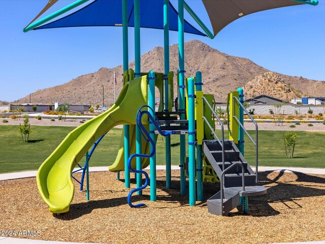 community playground with a mountain view and a lawn