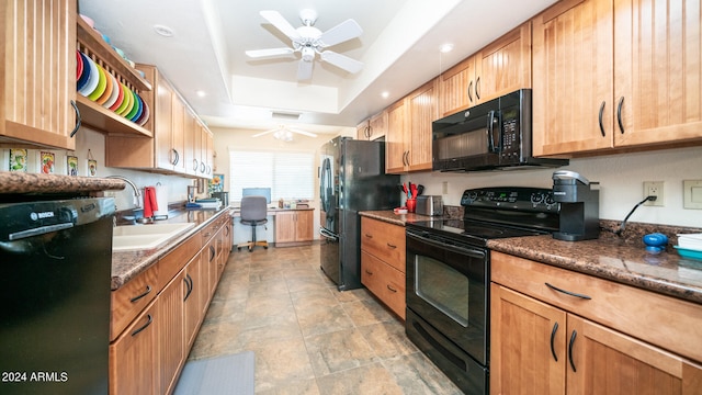 kitchen with sink, black appliances, a raised ceiling, dark stone countertops, and ceiling fan