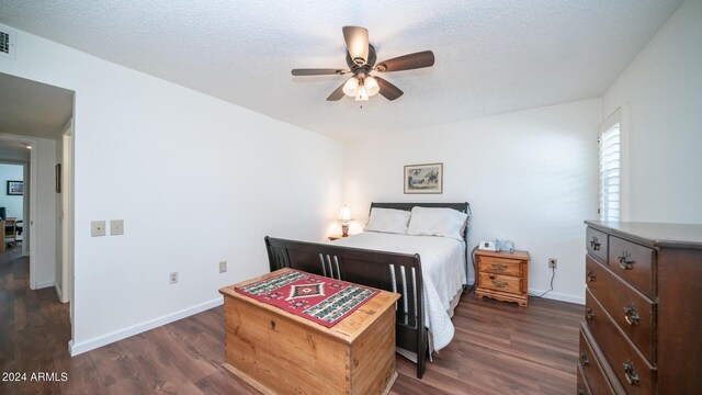 bedroom with ceiling fan, dark hardwood / wood-style floors, and a textured ceiling