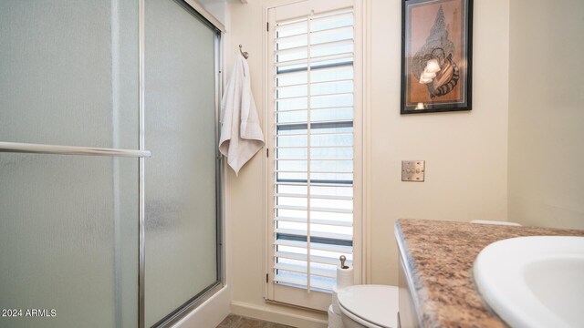 bathroom featuring vanity, a shower with shower door, toilet, and plenty of natural light