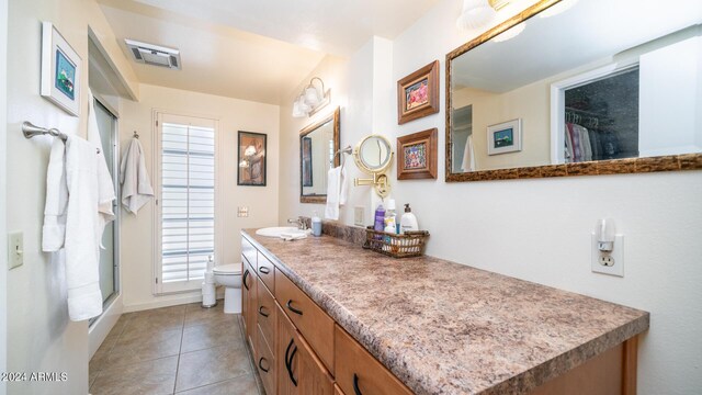 bathroom featuring vanity, a shower with shower door, toilet, and tile patterned floors