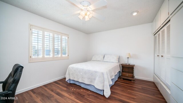 bedroom with a textured ceiling, a closet, ceiling fan, and dark hardwood / wood-style flooring