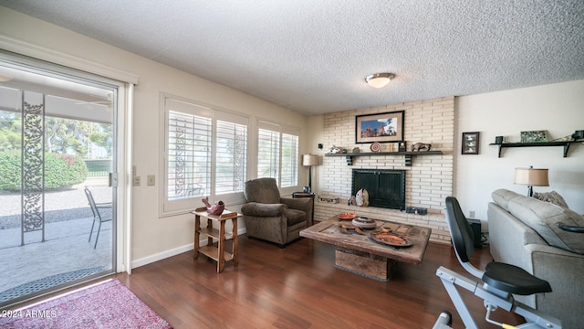 living room with a brick fireplace, a textured ceiling, and dark wood-type flooring