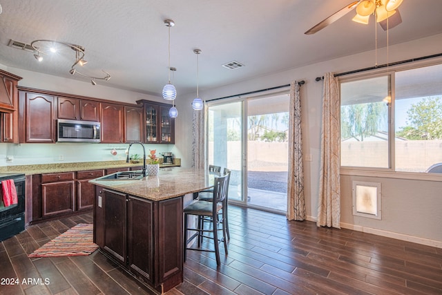 kitchen with dark hardwood / wood-style floors, black stove, sink, pendant lighting, and light stone counters