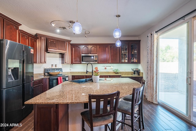 kitchen with an island with sink, dark hardwood / wood-style flooring, sink, pendant lighting, and stainless steel appliances