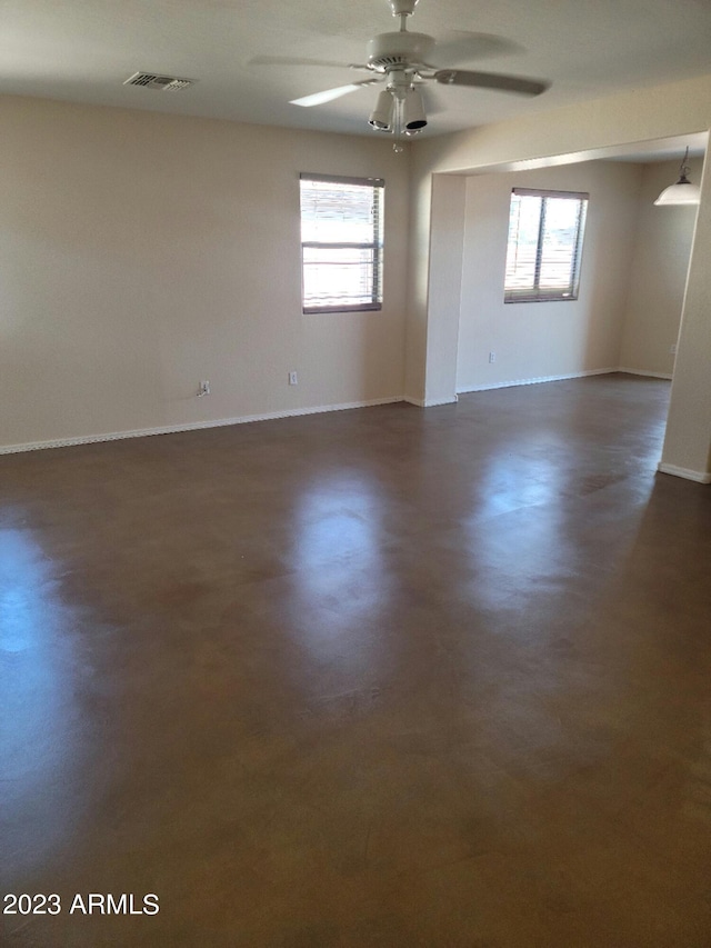 unfurnished room with a healthy amount of sunlight, visible vents, concrete floors, and ceiling fan