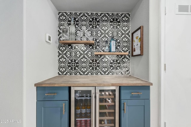 bar with blue cabinetry, beverage cooler, and wooden counters