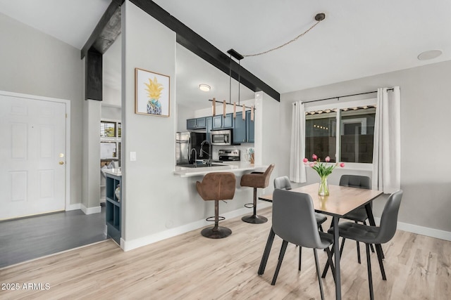 dining area featuring beam ceiling and light hardwood / wood-style flooring