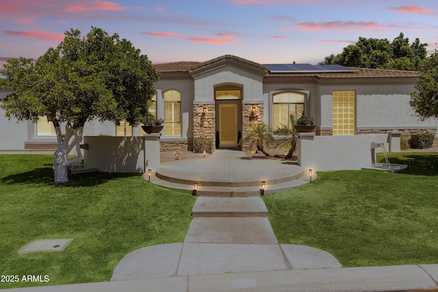 3410 E Inglewood Cir, Mesa, AZ 85213 - mediterranean / spanish-style house featuring a lawn, roof mounted solar panels, stone siding, and stucco siding