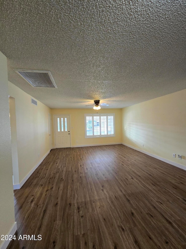 unfurnished room featuring ceiling fan, dark hardwood / wood-style flooring, and a textured ceiling