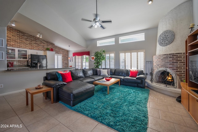 tiled living room with high vaulted ceiling, ceiling fan, brick wall, and a brick fireplace