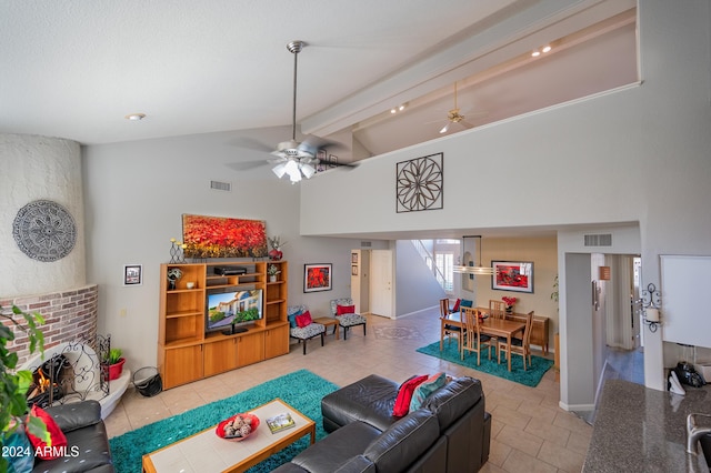 tiled living room with a brick fireplace, ceiling fan, beamed ceiling, and high vaulted ceiling