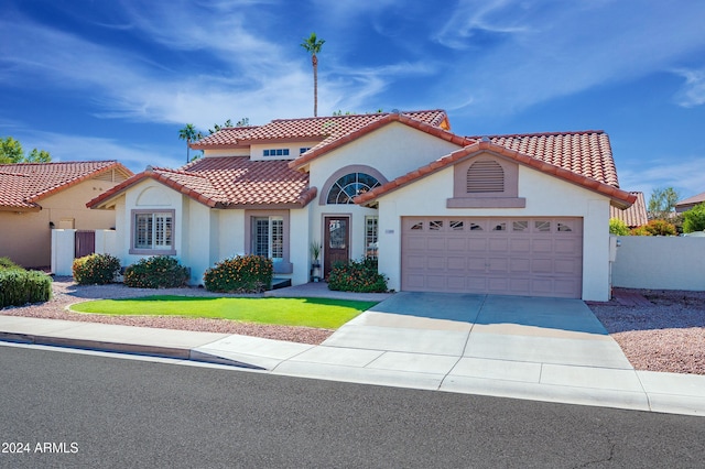 mediterranean / spanish home with a garage and a front lawn