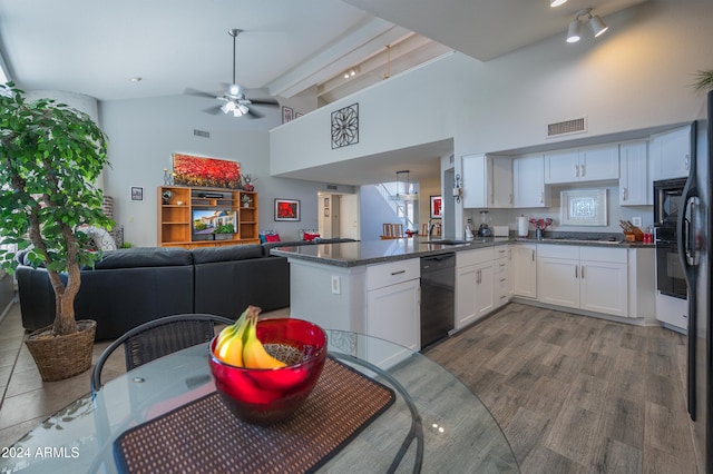 kitchen with kitchen peninsula, hardwood / wood-style flooring, dishwasher, dark stone countertops, and white cabinets