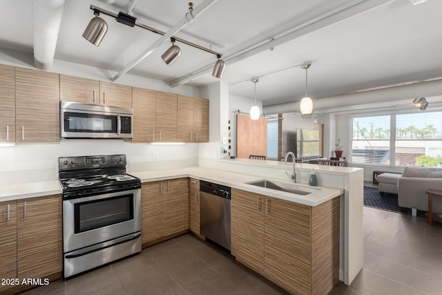 kitchen with appliances with stainless steel finishes, rail lighting, sink, dark tile patterned floors, and kitchen peninsula