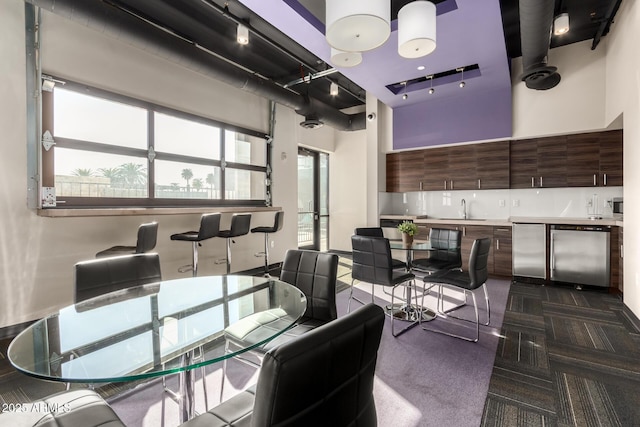 dining space with dark carpet, a towering ceiling, and sink