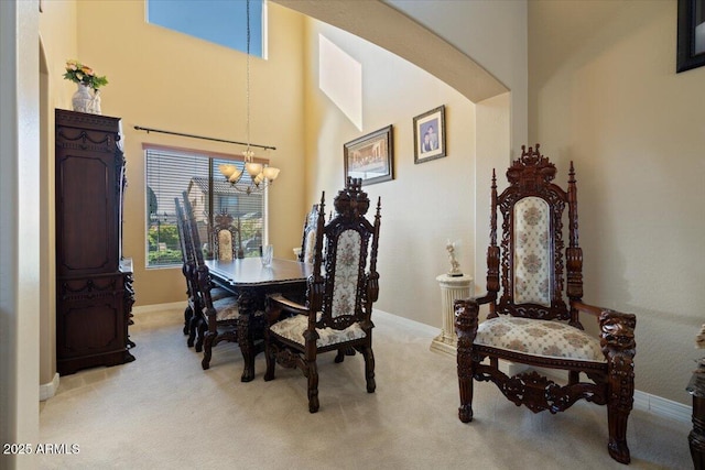 carpeted dining area with a towering ceiling and a chandelier