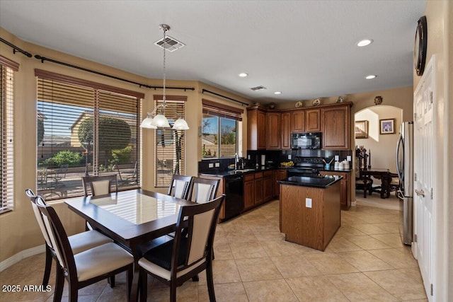 kitchen with sink, hanging light fixtures, black appliances, a kitchen island, and decorative backsplash