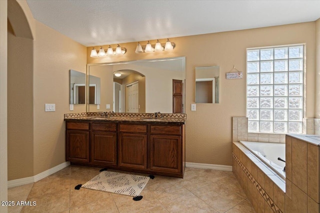 bathroom featuring tiled tub, vanity, and tile patterned flooring