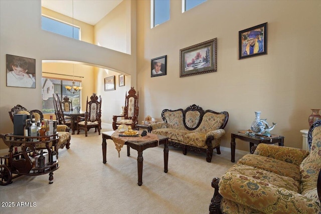 carpeted living room with a towering ceiling, a healthy amount of sunlight, and a chandelier