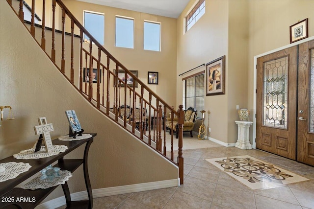 entrance foyer featuring french doors, a towering ceiling, and light tile patterned floors