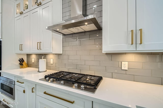 1890 E Sagittarius Pl, Chandler, AZ 85249 - kitchen with wall chimney exhaust hood, stainless steel gas cooktop, light countertops, white cabinetry, and tasteful backsplash