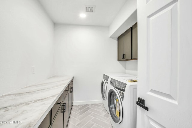 clothes washing area with washing machine and clothes dryer and cabinets