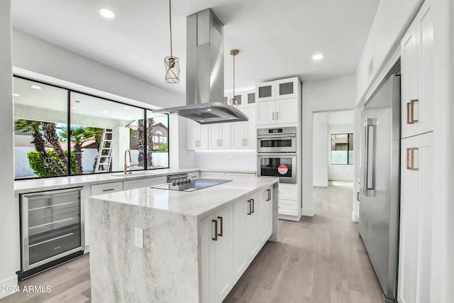 kitchen featuring stainless steel appliances, beverage cooler, decorative light fixtures, island range hood, and white cabinets