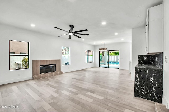 unfurnished living room featuring ceiling fan, light hardwood / wood-style floors, and a fireplace