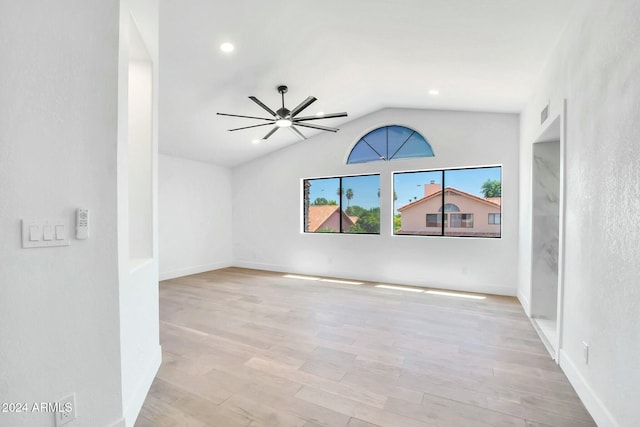 spare room with light wood-type flooring, vaulted ceiling, and ceiling fan