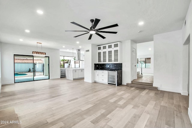 unfurnished living room featuring light hardwood / wood-style floors, wine cooler, and ceiling fan